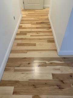 A hallway with hardwood floors and a door.