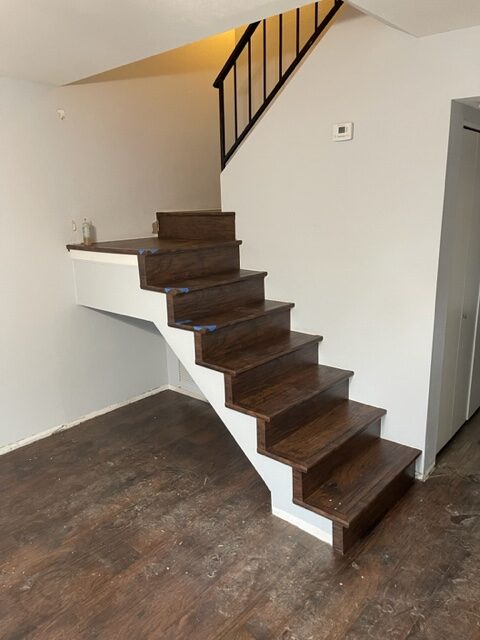 A staircase in a room with wood floors.