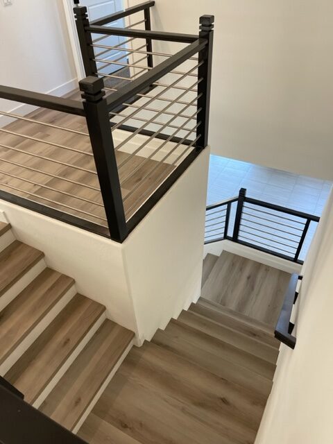 A staircase with black railing and wood flooring.