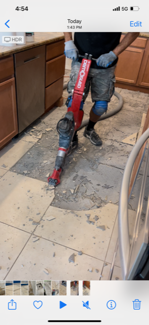 A man is using a machine to break a tile floor.