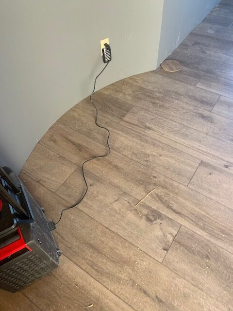 A cord is connected to a wood floor in a room.