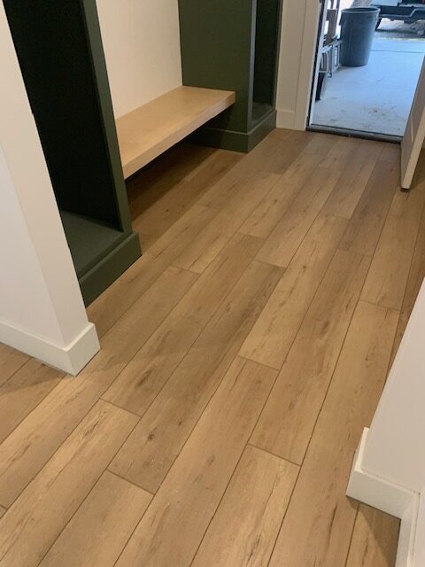 A hallway with wood floors and a bench.